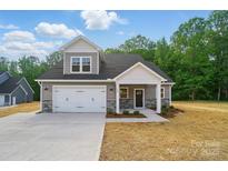 Charming two-story home featuring a gray exterior, stone accents, and a spacious two-car garage at 908 Westminster Dr, Statesville, NC 28677