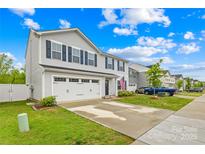 Charming two-story home with a two-car garage, blue shutters, and an American flag displayed near the front door at 115 Crownpiece St, Troutman, NC 28166