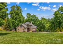 Stately brick home with a meticulously manicured lawn and mature trees offering shade and privacy at 141 Ridge Top Rd, Mooresville, NC 28117