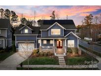Charming two-story home featuring a welcoming front porch, solar panels, and well-maintained landscaping at 1502 Matthew Mcclure Cir, Davidson, NC 28036