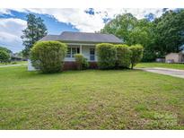 Charming home featuring a covered front porch and a well-maintained lawn and mature landscaping at 210 Park St, Bessemer City, NC 28016