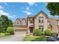 Charming two-story brick home featuring a manicured lawn, mature trees, and an attached two-car garage at 2346 Donnington Nw Ln, Concord, NC 28027