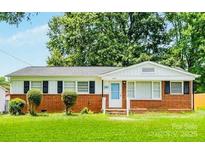 Charming single-story home with a brick facade, mature trees, and a well-maintained lawn at 2823 Albany Ln, Charlotte, NC 28205
