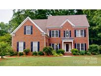 Charming red brick home featuring black shutters, lush landscaping, and a well-maintained lawn at 4066 Belle Meade Cir, Belmont, NC 28012
