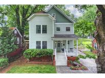 Charming two-story home with a covered front porch, manicured lawn, and lush landscaping adding to its curb appeal at 409 W Kingston Ave, Charlotte, NC 28203