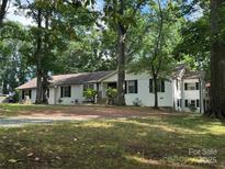Charming white brick home with black shutters nestled amongst mature trees on a spacious lot at 603 Sunnybrook Dr, Monroe, NC 28110