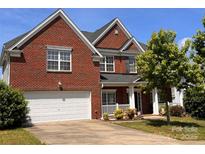 Charming two-story brick home with a well-manicured lawn and attached two-car garage at 6227 Castlecove Rd, Charlotte, NC 28278