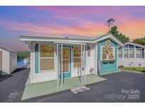 Charming home with teal and white exterior, decorative accents, and delightful curb appeal under a colorful sunset sky at 125 Maple St, New London, NC 28127