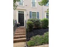 Charming two-story townhome featuring a black front door, brick stairs, and manicured landscaping at 13838 Winmau Ln, Huntersville, NC 28078