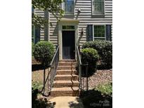 Inviting front door with brick steps, enhanced by black railing and verdant bushes at 13838 Winmau Ln, Huntersville, NC 28078