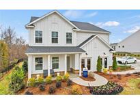 Charming new construction home boasts modern farmhouse design, inviting front porch, and professionally landscaped yard at 15008 Meadows Hunt Ln # 156, Huntersville, NC 28078