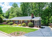 Charming brick home with lush landscaping, a screened porch, and a well-manicured front yard at 1602 Brentwood Dr, Newton, NC 28658
