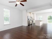 Spacious living room with dark wood floors and white walls leading to the kitchen at 2448 Mariners Cove Ln, Denver, NC 28037