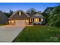Charming brick home boasts a manicured lawn, a two-car garage, and a welcoming front porch with lights on at dusk at 3817 Arial Ln # 145, York, SC 29745