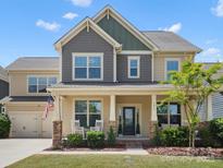 Inviting two-story home featuring a covered porch, manicured lawn, and charming curb appeal on a sunny day at 5013 Hamilton Mill Dr, Waxhaw, NC 28173