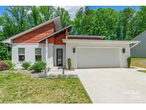 Modern home with white stucco, wood accents, black trim, large garage and well maintained yard at 7728 Shalom Dr, Charlotte, NC 28216