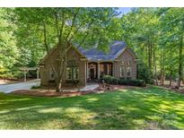 Charming brick home featuring a lush, landscaped front yard and inviting entrance, nestled amongst mature trees at 131 Sierra Woods Dr, Troutman, NC 28166