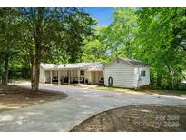 A charming home exterior featuring a covered outdoor area and a lush, green landscape at 1917 Tom Sadler Rd, Charlotte, NC 28214