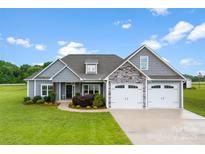 Beautiful home exterior with manicured lawn, gray siding, stone accents, and a three-car garage at 210 Dorothy Dr, China Grove, NC 28023