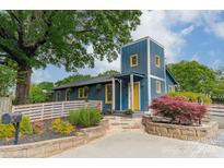 Charming blue two-story home featuring a yellow door, beautiful landscaping and a lush green tree canopy at 2915 Wesley Ave, Charlotte, NC 28205