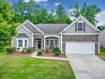 Charming single-Gathering home featuring stone accents, a well-manicured lawn, and an attached two-car garage at 6021 Piscataway Ct, Rock Hill, SC 29732