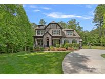 Beautiful two-story home with stone accents, lush landscaping, and a winding driveway leading to a three-car garage at 6171 Willow Farm Dr, Denver, NC 28037