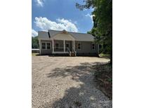 Charming single story home featuring a covered porch, gravel driveway and well-manicured lawn at 7426 Hambright Rd, Huntersville, NC 28078
