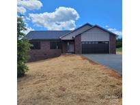 New brick home with a modern two-car garage, paved driveway, and freshly strawed yard under a sunny sky at 8222 Madison Ln, Hickory, NC 28602
