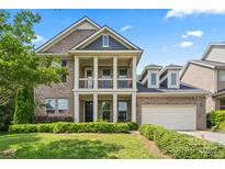 Charming brick home featuring a two-story porch, manicured lawn, and attached garage at 8514 Ellington Park Dr, Charlotte, NC 28277