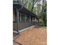 Charming brick home exterior featuring a covered front porch with tasteful gray accents and wood-chip landscaping at 1002 Hemlock Dr, Shelby, NC 28150