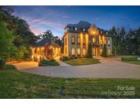 Elegant exterior of a grand home, featuring manicured landscaping and a circular driveway with a guest house at dusk at 1118 Seminole Dr, Fort Mill, SC 29707