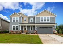 Two-story home with gray siding, stone accents, covered porch, and attached two-car garage at 1119 Bellshill Dv, Indian Trail, NC 28079