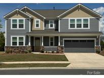 Charming two-story home with a covered front porch and a two-car garage, complete with a landscaped yard at 1119 Bellshill Dv, Indian Trail, NC 28079