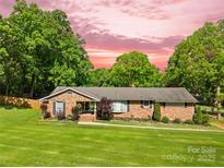 Charming brick ranch home features a lush lawn, mature trees, and a welcoming front entrance at 245 Kingsway Cir, Charlotte, NC 28214