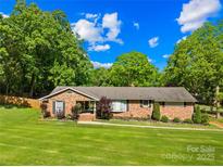 Charming brick ranch-style home with a well-manicured lawn and mature trees providing shade at 245 Kingsway Cir, Charlotte, NC 28214