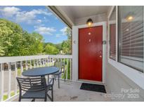 Inviting balcony with a table and chairs and bright red front door offering a place to sit and enjoy the view at 3201 Heathstead Pl # C, Charlotte, NC 28210