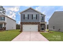 New two-story home boasts gray siding, stone accents, a two-car garage, and a well-manicured lawn at 581 E Sparkleberry St, Chester, SC 29706