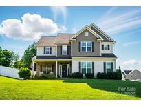 Charming two-story home featuring a landscaped yard, welcoming porch, and beautiful architectural details at 6314 Bluffton Ln, Midland, NC 28107