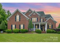 Charming two-story brick home with a well-manicured lawn and landscaping at 8962 Landsdowne Ave, Harrisburg, NC 28075