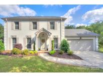 Charming two-story painted brick home with a manicured lawn, lush landscaping, and a welcoming front entrance at 10016 Tealridge Ln, Charlotte, NC 28277