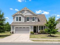 Charming two-story home with manicured lawn, gray siding, and attached two-car garage at 1305 Kings Grove Dr, York, SC 29745