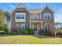 Beautiful two-story home featuring stone and shingle siding, manicured lawn, and an inviting front porch at 16831 Alydar Commons Ln, Charlotte, NC 28278