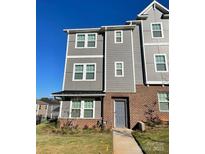Three-story townhouse featuring gray siding, brick accents, and well-maintained landscaping at 2019 Tears Ln, Charlotte, NC 28217