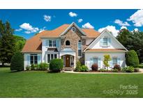 Beautiful two-story home with a stone facade, well-manicured lawn, and charming light blue shutters at 21216 Norman Shores Dr, Cornelius, NC 28031