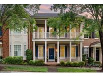 Charming two-story brick home with a welcoming front porch and balcony, surrounded by lush landscaping and mature trees at 239 N Faulkner Way, Davidson, NC 28036