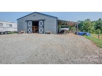 Large metal barn with open sliding doors and covered parking featuring ample gravel space at 2676 Will Schronce Rd, Iron Station, NC 28080