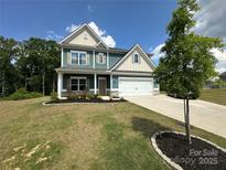 Charming two-story home features a well-manicured lawn, a two-car garage, and inviting front porch at 348 Ox Bow Cir, Mount Holly, NC 28120