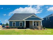 Charming single-story home with blue siding, stone accents, covered porch, and beautifully landscaped front yard at 407 Bent Burr Crk, York, SC 29745