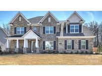 Inviting exterior of stone-accented home with shuttered windows and meticulously maintained front yard at 809 Brown Creek Dr, Matthews, NC 28104