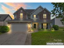 Charming two-story home featuring a stone-accented facade, well-manicured lawn, and attached two-car garage at 9639 Ravenscroft Nw Ln, Concord, NC 28027